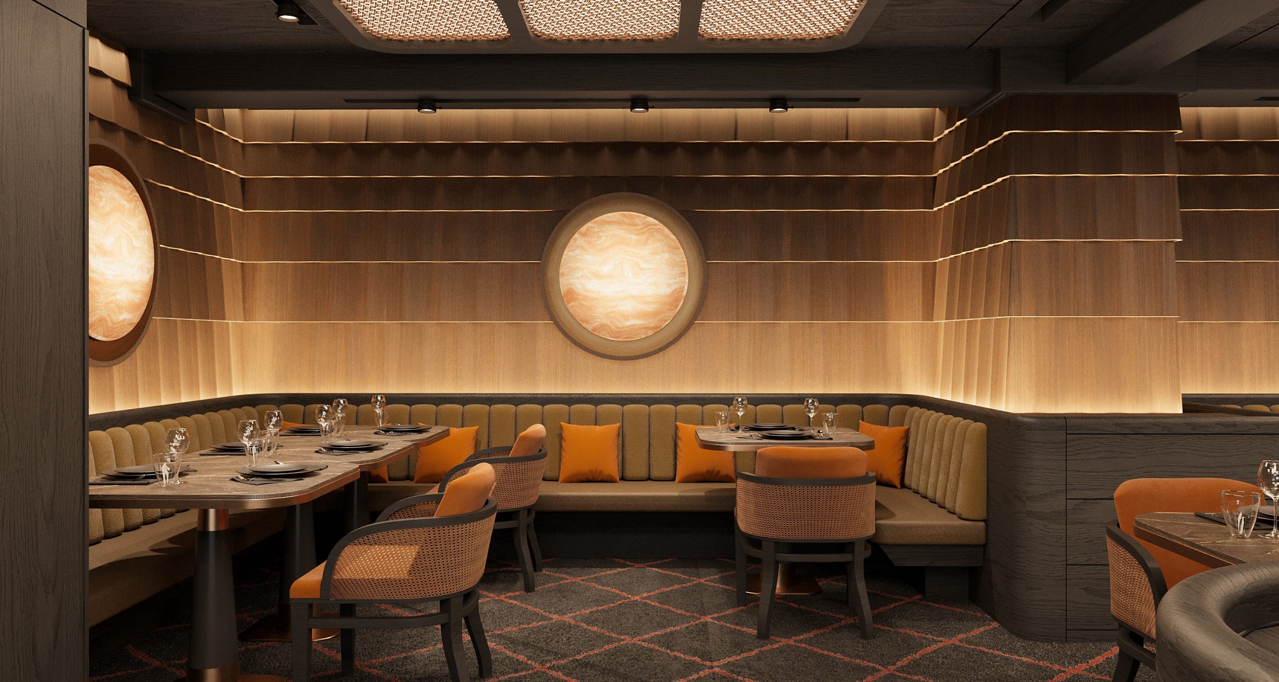 Ein modernes Restaurant mit holzgetäfelten Wänden, geschwungenen Kabinen mit beigen Sitzmöbeln und orangefarbenen Kissen, runden Tischen zum Essen und sanfter Beleuchtung mit einer runden, hinterleuchteten Wand.